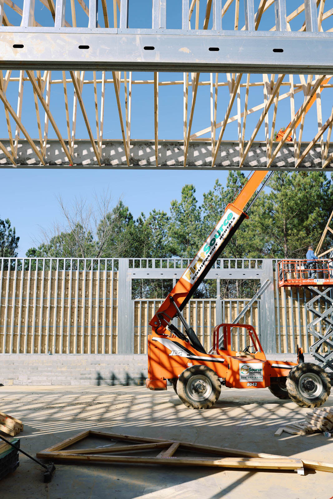 Telehandler on a slab below cold-formed steel wall panels and a truss line